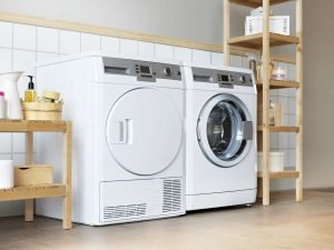 A compact washer and dryer set in a cozy, small laundry room with light-colored walls and minimal decor.